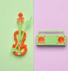 Miniature boombox audio tape recorder and violin on a pastel background