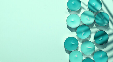 Aroma tea candles with palm leaf shadow on blue background. Top view. Copy space