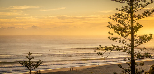 Beautiful golden sunrise over early morning surfers, Kirra Beach, Queensland