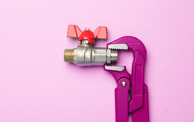 Adjustable wrench with ball valve on a pink background