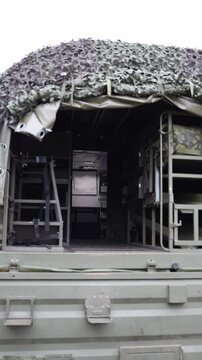 Vertical screen interior of military transport truck reveals rows of bunk beds and gear storage under camo canopy designed for field deployment with functionality and compact living in mind