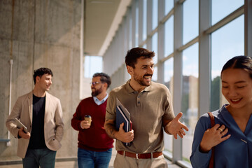 Happy entrepreneur talking to his colleague while going on business meeting in office.