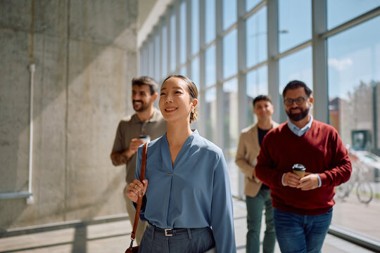 Group of business managers walking though hallway of office building.