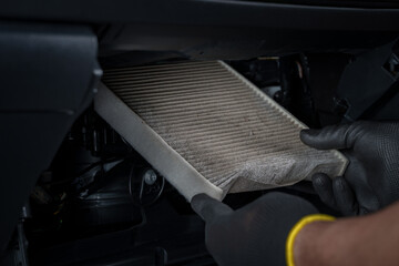 Dirty cabin air filter being replaced in a car.
Mechanic hands with black gloves holding dirty...