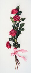 Obraz premium A simple arrangement of red roses tied with a pink ribbon against a white backdrop.