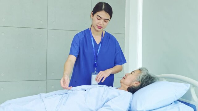 Female physiotherapist treats shoulder paralysis and arm numbness elderly woman lying on bed. Nurse treats pain by lifting right arm training to treat muscle weakness in hospital.