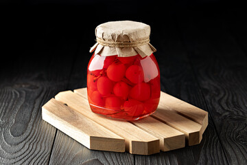 Jar of Pickled Cherries on Dark Wooden Background