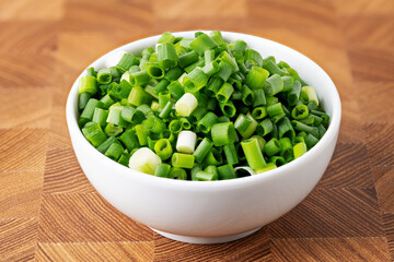 Chopped Green Onions in White Bowl on Wooden Background