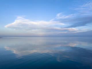 Evening calm and smooth lake surface under soft clouds
