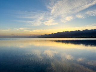 Quiet mountain lake, evening light on the water, Kyrgyzstan. Still water and mountain reflection in the lake.