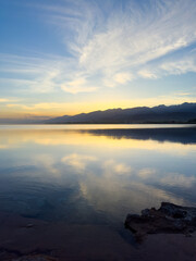 Quiet mountain lake, evening light on the water, Kyrgyzstan. Still water and mountain reflection in the lake.
