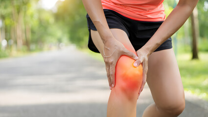 Runner clutches her knee in pain on a sunlit path