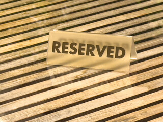 Reserved sign on wooden table with slatted pattern and glass reflection