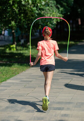 A girl is running with a rainbow hula hoop