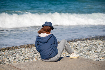 A woman is sitting on a beach with her hat on