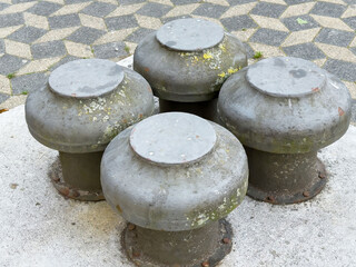 Rusty metal bollards on geometric patterned pavement with moss and lichen