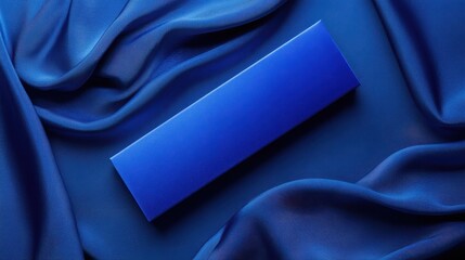 A vibrant cobalt blue rectangular box rests on a bed of draped satin.