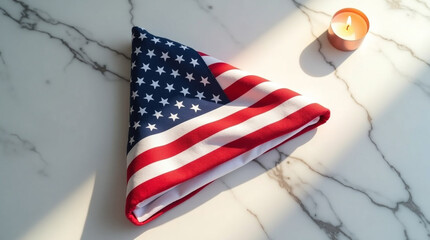 Folded american flag rests beside a softly glowing candle on a marble surface, bathed in gentle light