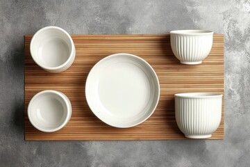 White ceramic bowls and plate arranged on a bamboo placemat.