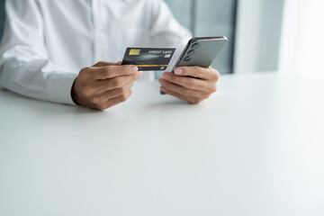 Asian Man paying with credit card on smart phone at office. Male Using Smartphone for Shopping electronic wallet Online 