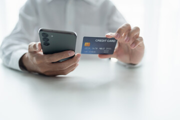 Asian Man paying with credit card on smart phone at office. Male Using Smartphone for Shopping electronic wallet Online 