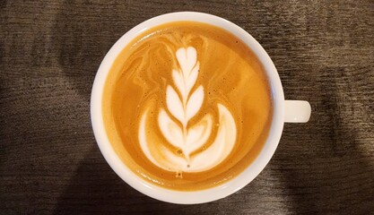 Beautiful Latte Art on Creamy Coffee in White Mug on Wooden Table