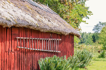 Wooden ladder hanging on the wall on a red barn in the countryside