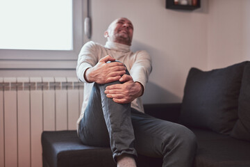Man with painful knee and leg injury at home.