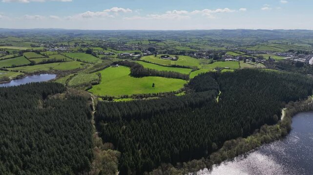 Bellamont House, County Cavan, Ireland, April 2023. Drone pulls back over forest, lake and Irish countryside under sunny blues skies, stunning nature view.