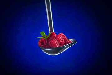 Fresh Raspberries in Stainless Ladle on Blue Background