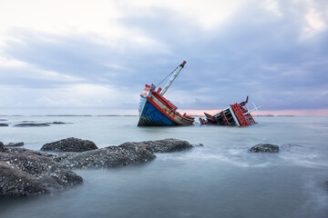 Old wrecked fishing boat in sea at dusk on coast of Ang Sila Village, Saensuk Sub-district,...