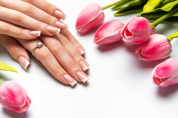 Woman showing french manicure and pink tulips on white background