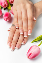 Woman showing french manicure and pink tulips on white background