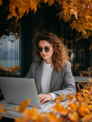 stylish young businesswoman with curly hair using laptop in outdoor 