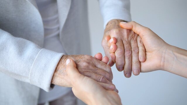Close up image capturing a young caregiver gently holding the hands of a senior woman, conveying comfort, support, and deep empathy within a compassionate healthcare environment