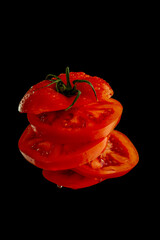 Juicy tomato cut into slices suspended in air with a kitchen knife. Fresh, dynamic concept of cooking and food preparation.