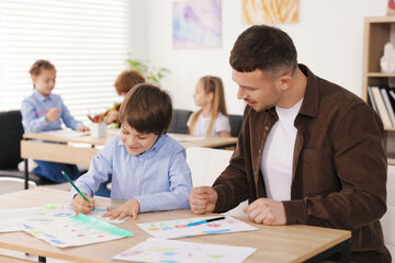 Fototapeta premium Man teaching kid to draw at painting lesson indoors, selective focus
