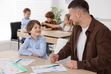 Man teaching kid to draw at painting lesson indoors, selective focus
