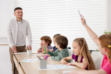 Man teaching kids to draw at painting lesson indoors