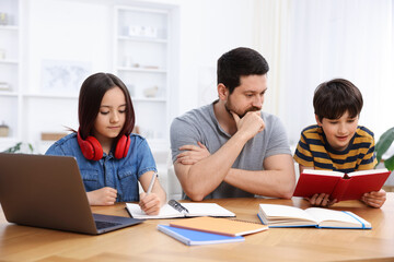 Fototapeta premium Father helping his kids with homework at wooden table indoors