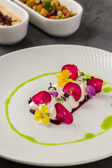 Colorful beetroot slices with goat cheese, garnished with edible flowers