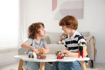 Cute little brothers playing with toys at table indoors