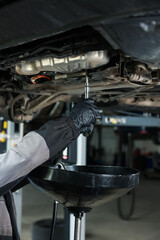 Worker removing dirty old motor oil from car engine, closeup