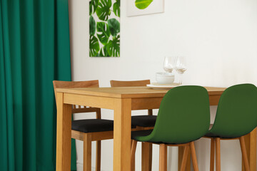Dining table and chairs in room. Interior design with green color accent
