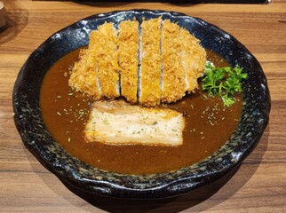 Crispy Pork Cutlet in Rich Brown Sauce with Garnish on Wooden Table