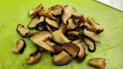Sliced Shiitake Mushrooms on Bright Green Cutting Board Background
