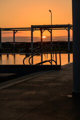 Still pool water reflecting dramatic sunset colors in a quiet residential complex on the Mediterranean island