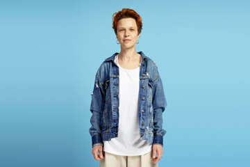 Confident artist posing wearing denim jacket and white t shirt on blue background
