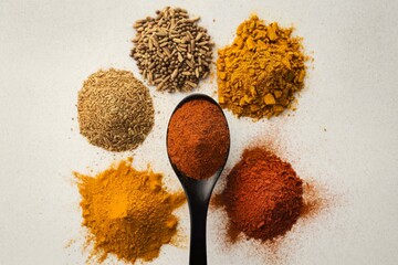 A photo of ground spices in a black spoon