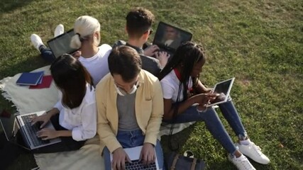 Group of students study with laptop on the green grass - Powered by Adobe